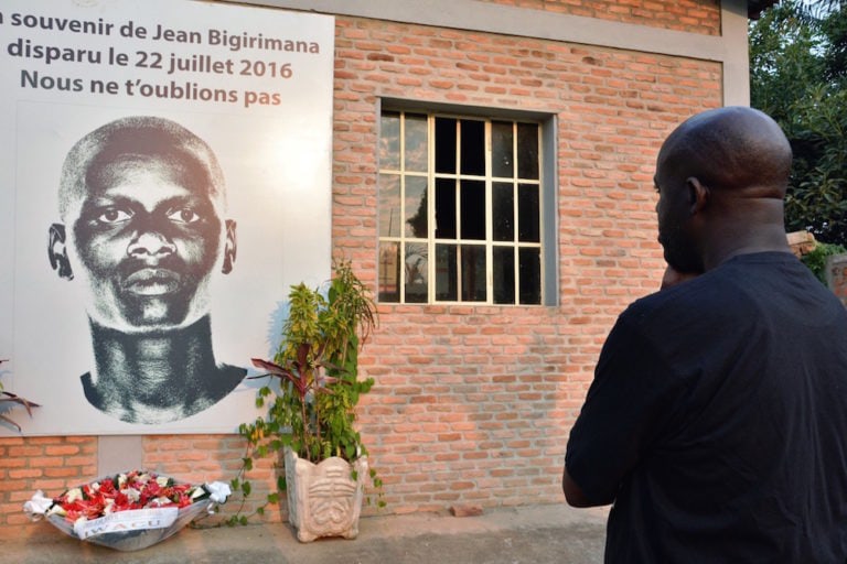 A man stands in front of a plaque in honor of Burundian journalist Jean Bigirimana, during a commemoration to mark one year after his disappearance, in Bujumbura, 21 July 2017, STRINGER/AFP via Getty Images