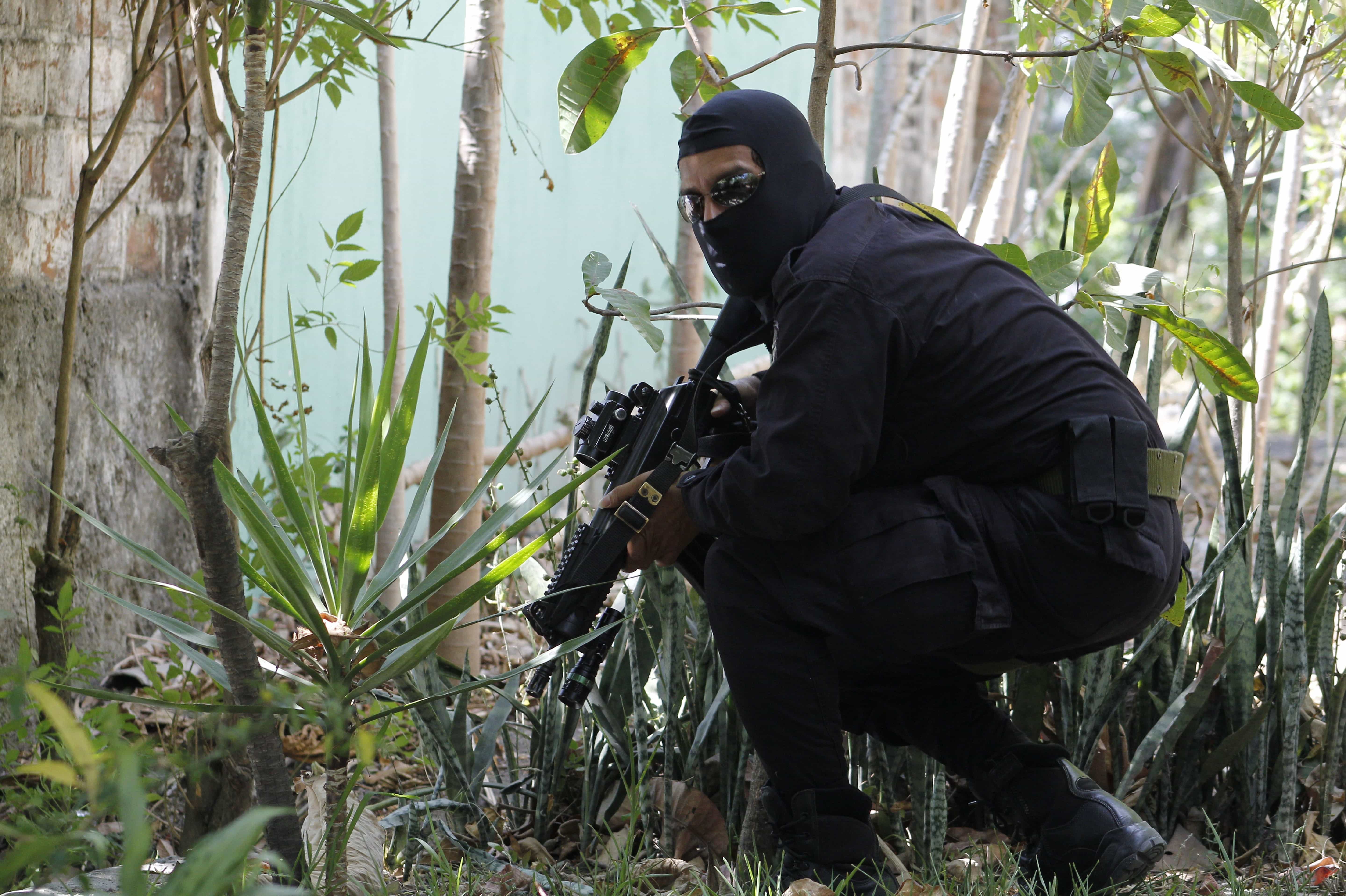 In this 5 April 2016 photo, a masked and armed policeman crouches as he patrols a gang controlled neighborhood in San Salvador, El Salvador, AP Photo/Alex Peña