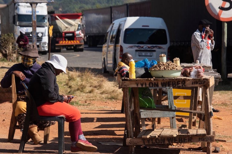 A vendor checks her phone, outside the Oshoek border-post on the South African side of the border with Eswatini, 2 July 2021, as calm returned to Eswatini after days of pro-democracy protests. RODGER BOSCH/AFP via Getty Images