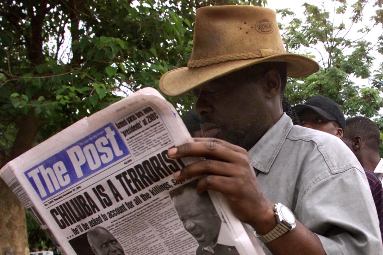 A Zambian man reads "The Post" paper while queueing to cast his vote in Lusaka, 27 December 2001, REUTERS/Juda Ngwenya